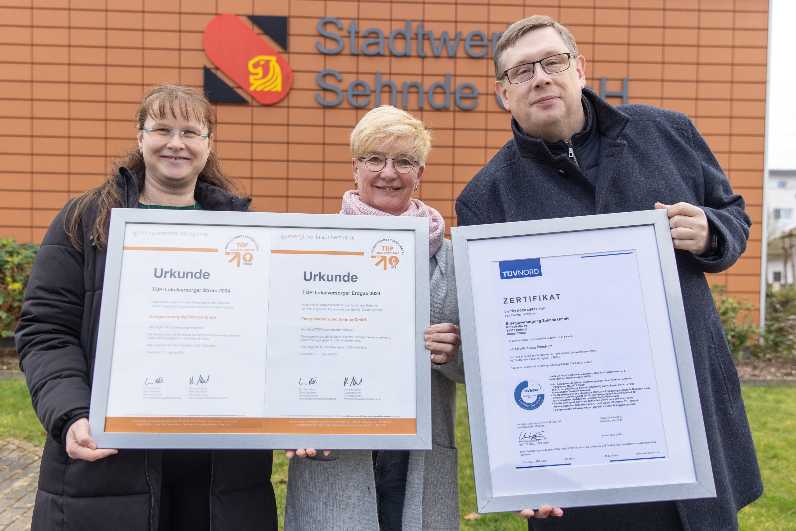 Nicole Sander, Silke Schlüter und Cris Wallendorf, drei Mitarbeitende der EVS, präsentieren Urkunden TOP Lokalversorger 2024 für Strom und Gas sowie das TÜV Zertifikat für Ökostrom aus Niedersachsen