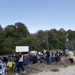 Foto von der Kinoleinwand und Besucherinnen und Besuchern beim Open-Air Kino im Waldbad am 04.07.2025