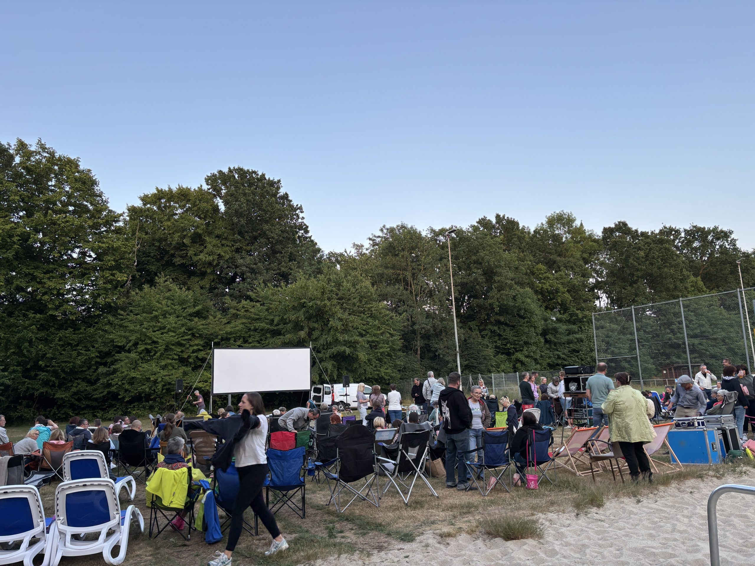 Foto von der Kinoleinwand und Besucherinnen und Besuchern beim Open-Air Kino im Waldbad am 04.07.2025